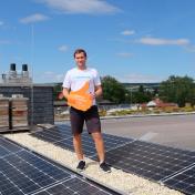 Marcel Schwalbach, Vorstand bei der Energiegenossenschaft Ilmtal, steht auf einem mit Photovoltaik bedeckten Dach