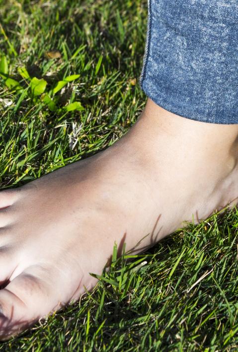 Ein nackter Fuß auf grünem Rasen