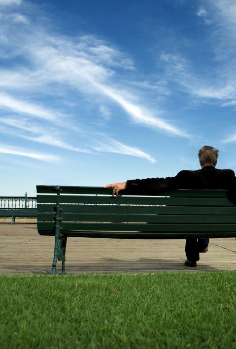 man sitting on a bench looking at the sky 
