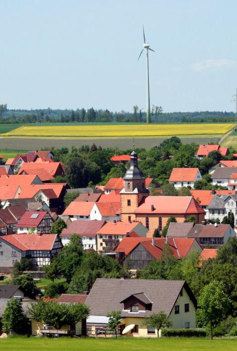 Deutsches Dorf mit Windkraftanlagen im Hintergrund
