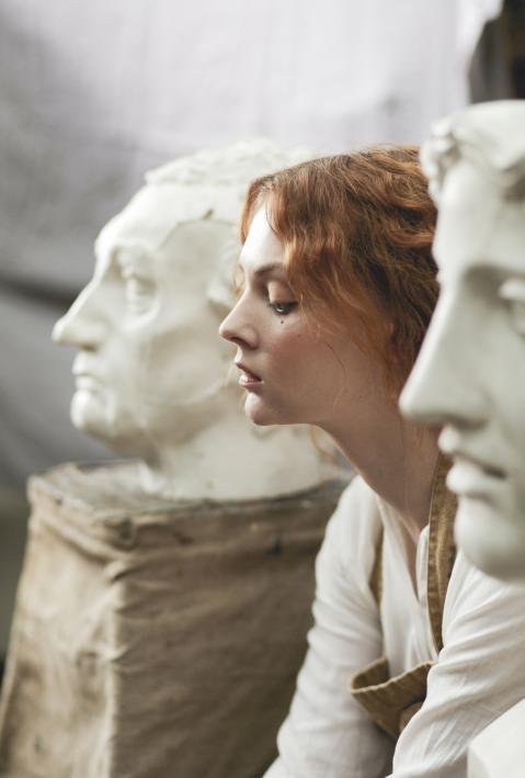 Female face between two white statues heads