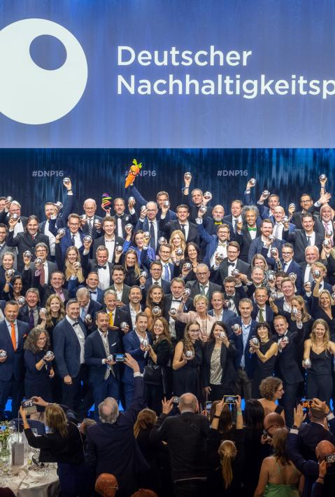 Die Gewinner*innen des Deutschen Nachhaltigkeitspreises 2023 jubeln mit den Trophäen auf der Bühne
