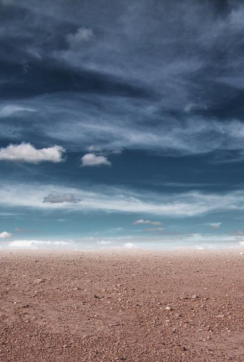 Graue Wolken hängen über karger Wüste. 