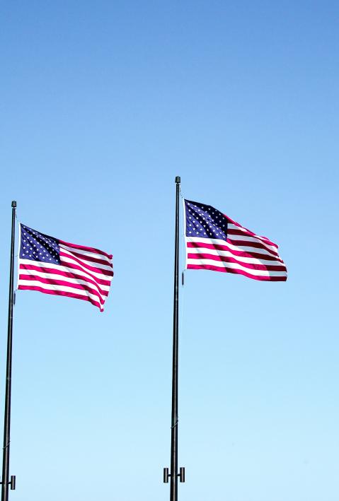 Four US flags on poles are waving in the wind
