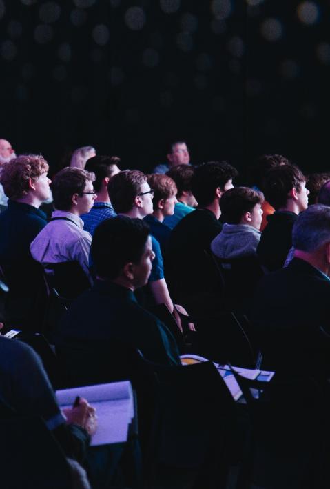 People sitting in rows of chairs at a conference. 