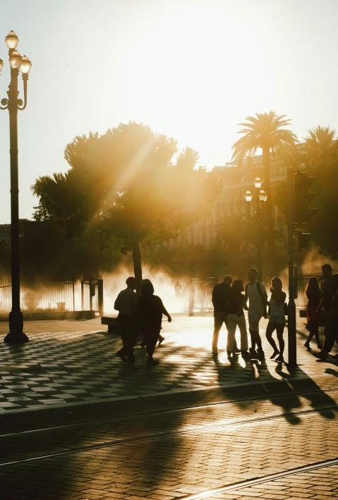 Silhouette von Menschen, die auf einer Straße in Frankreich herumlaufen, im Gegenlicht, während Nebel im Hintergrund aufsteigt