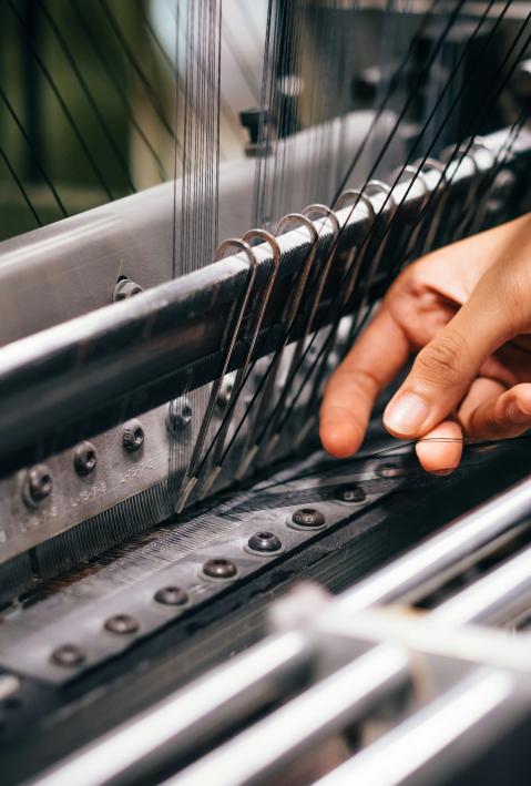 F&auml;den werden an eine Personenfixiermaschine zum Herstellen von Textilien angebracht