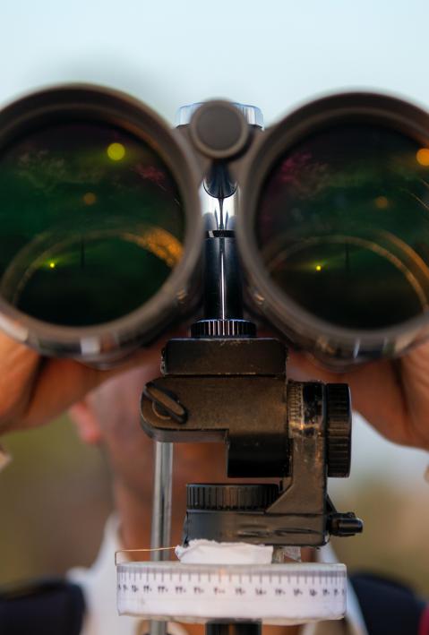 Person looks through large binoculars.
