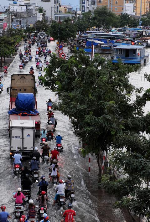 HO CHI MINH CITY, VIET NAM- OCT 18, 2016: Awful flooded street at Asian city, crowd of people ride motorcycle wade in water from tide on road, climate change make sea level rise, Vietnam