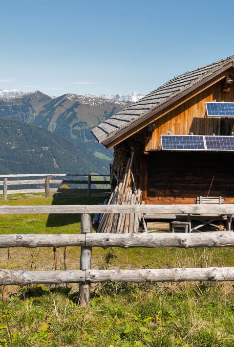 Wooden shepherd lodge with solar panels on a highland pasture with Alpine mountain landscape in Western Carinthia, Austria.