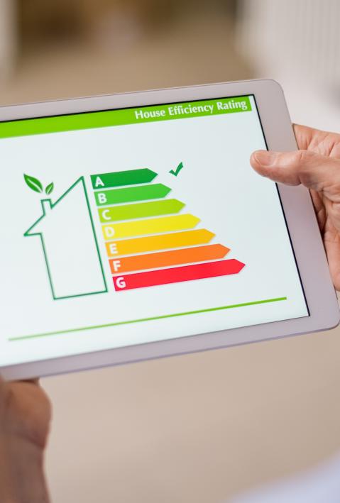 Hand holding digital tablet and looking at house efficiency rating. Detail of house efficiency rating on digital tablet screen.
