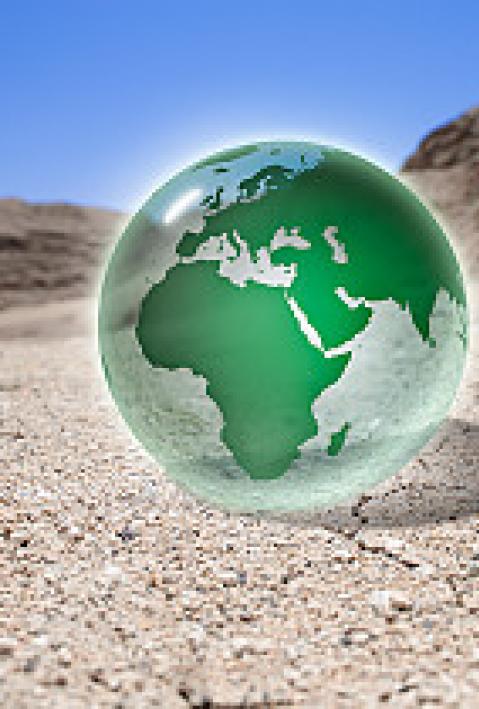 Green glass globe sitting in desert