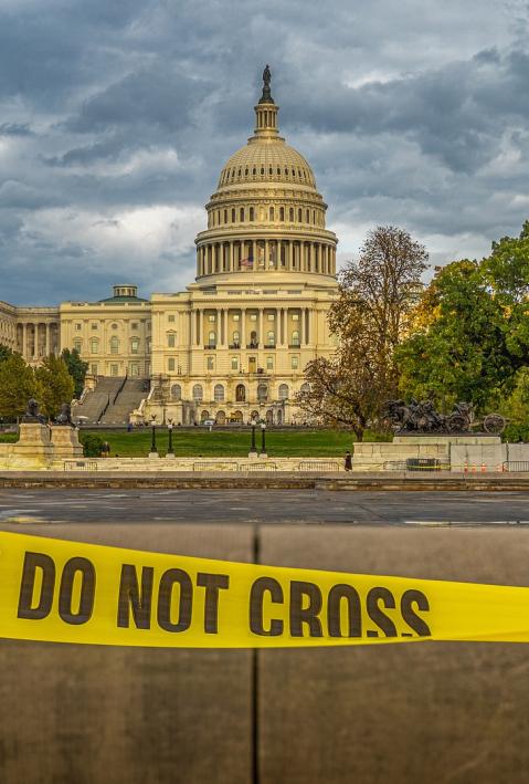 The US Capitol in Washington, DC. A yellow tape with the inscription Police Line Do Not Cross in the lower foreground.