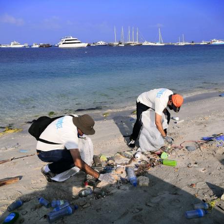 Zwei Frauen reinigen den Strand von Plastik. 