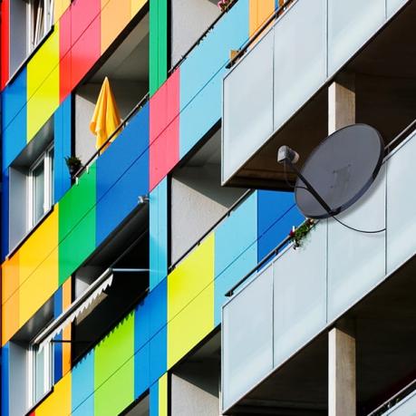 Ein Gebäude mit Balkonen, deren Fronten in farbige Vierecke angemalt sind