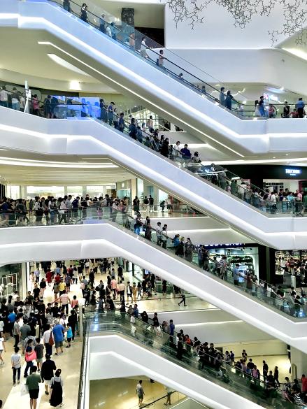 Crowded shopping centre with people standing on escalators