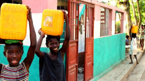 Zwei Kinder tragen Wasserbehälter auf ihren Köpfen
