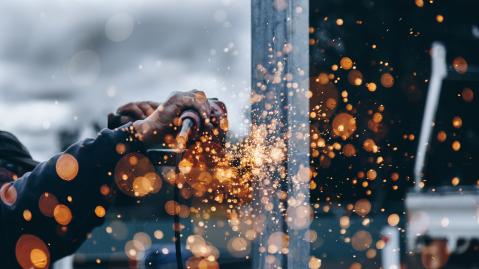 Workers' hands with welding equipment and sparks