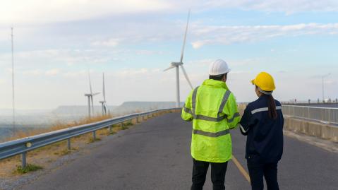Two people survey wind turbines
