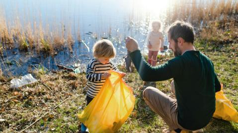 Ein Mann und zwei Kinder sammeln am Sumpf Müll ein