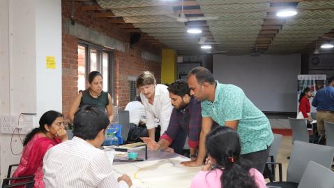 People sitting and standing around a table in Hubbli, India, during the Training of Trainers Workshop of the Circular Economy Catalyst