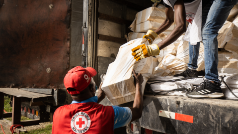 Mitarbeitende vom Roten Kreuz laden in Haiti einen Wagen mit Hilfsgütern aus