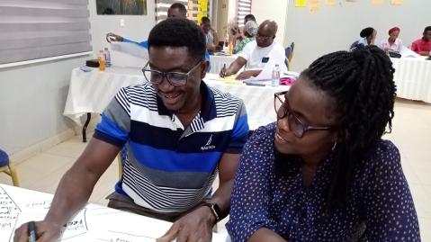A man and a woman at the SEED Starter Workshop in Ghana write ideas on a sheet of paper
