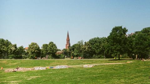 Grünfläche mit Kirchturm im Hintergrund. 
