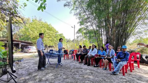 Employees of ListenField in Thailand sitting on small red plastic chairs listening to two people holding a presentation