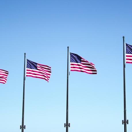 Four US flags on poles are waving in the wind