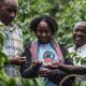 three persons from Gorilla Conservation Coffee looking at coffee beans in lush green environment, laughing