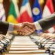 Handshake between diplomats at an international meeting with various country flags in the background, symbolizing global cooperation