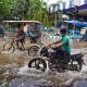People in Kolkata ride bicycles and motorbikes through flooded streets and heavy rain