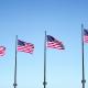 Four US flags on poles are waving in the wind