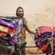 Indischer Verkäufer, der Kleidung auf einem Fahrrad verkauft. 