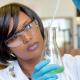 African female researcher with glass equipment in the lab - soft focus on glass and hands.