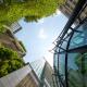 Low-angle-Aufnahme von modernen Glasgebäuden und Grün mit klarem Himmelshintergrund.